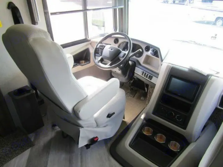 Spacious RV rental cockpit with light-colored driver's seat, steering wheel, and infotainment dash.. Fleetwood Bounder 2022