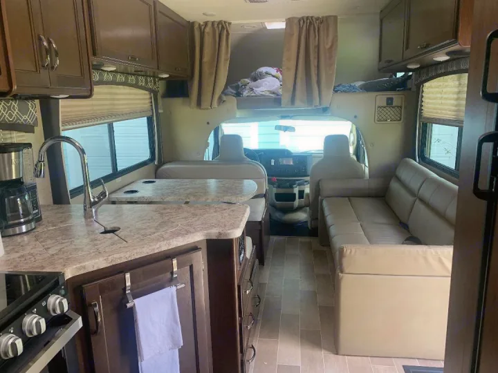 Spacious rv rental interior featuring a full kitchen with sink, dinette, and comfortable sofa, ready for adventure.. Thor Motor Coach Chateau 2020