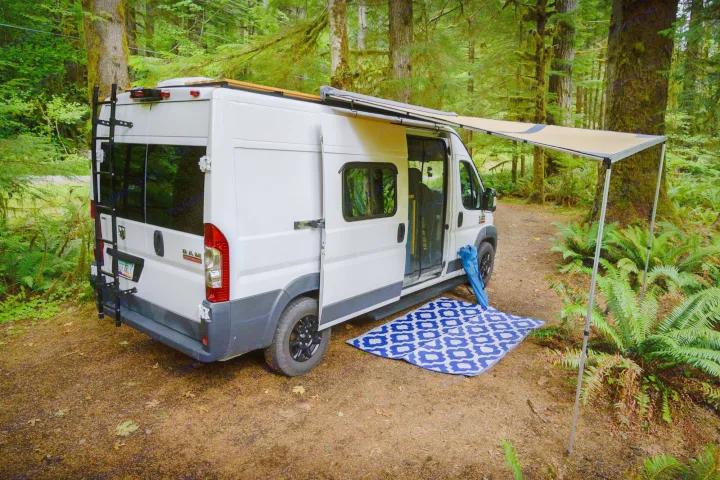 This RV rental in a lush forest features an extended awning & ground mat for comfortable camping.. Dodge RAM Promaster 2500 159' Wheelbase 2017