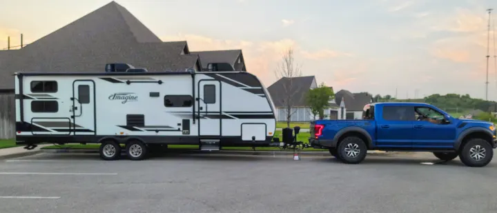 A powerful blue pickup truck is perfectly hitched to a spacious white RV travel trailer, ideal for your next RV rental adventure.. Grand Design 2800BH 2021