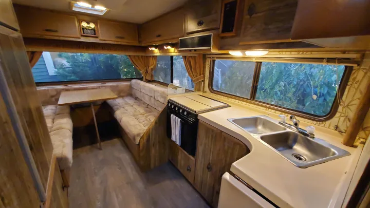 Step inside this cozy rv rental! Features a vintage dinette, full kitchen with double sink, and ample wood cabinets.. Lazy Daze 22 1987