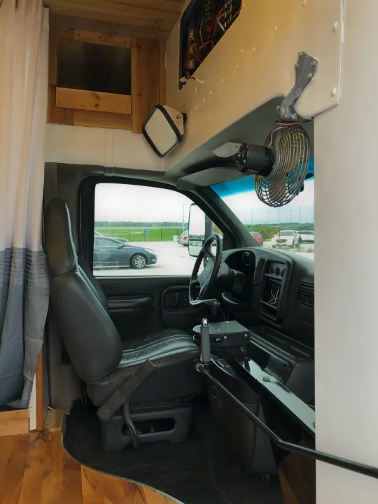 RV rental van interior: View of the driver's area with custom woodwork, dashboard, and an overhead fan.. Chevy Express 3500 Mini Bus 2002