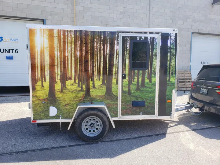 This RV rental trailer features a vibrant forest graphic wrap, hitched to a Honda Odyssey. Perfect for an outdoor adventure!. Neo Trailer NAV105S 2020