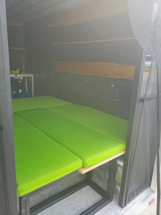 RV rental interior features bright green bed cushions and a compact sink area.. Neo Trailer NAV105S 2020