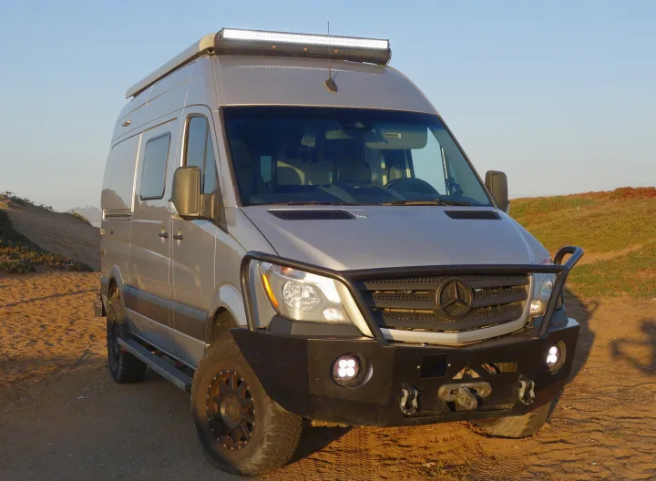Front view of a customized, light-tan Mercedes Sprinter camper van, equipped for off-road RV rental adventures.. Winnebago Revel 2019