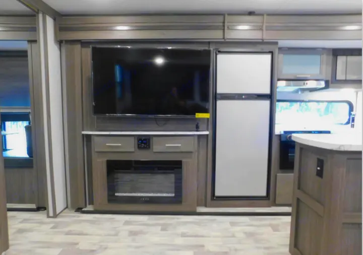 Modern RV rental interior featuring a large flat-screen TV, electric fireplace, and spacious refrigerator in the living area.. Dutchmen Other 2021