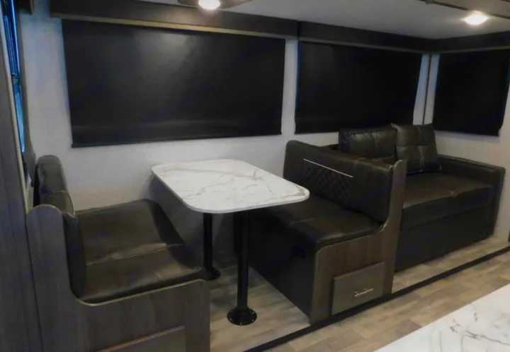Comfortable RV rental living space with a dark dinette, light marble table, and large windows with blackout blinds.. Dutchmen Other 2021