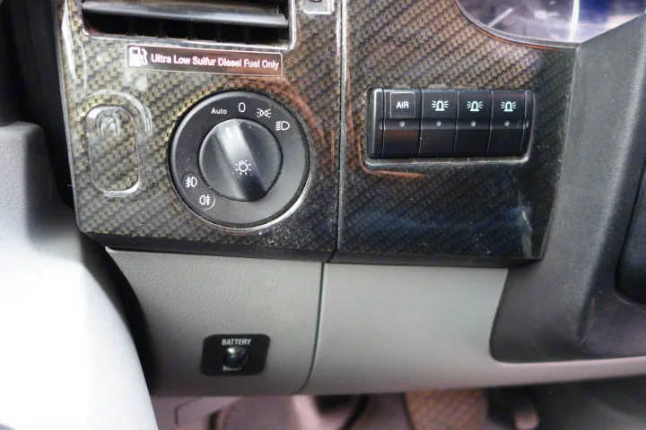 RV rental interior: Dashboard with light controls, auxiliary switches, diesel fuel reminder, and battery boost button.. Winnebago Revel 2019