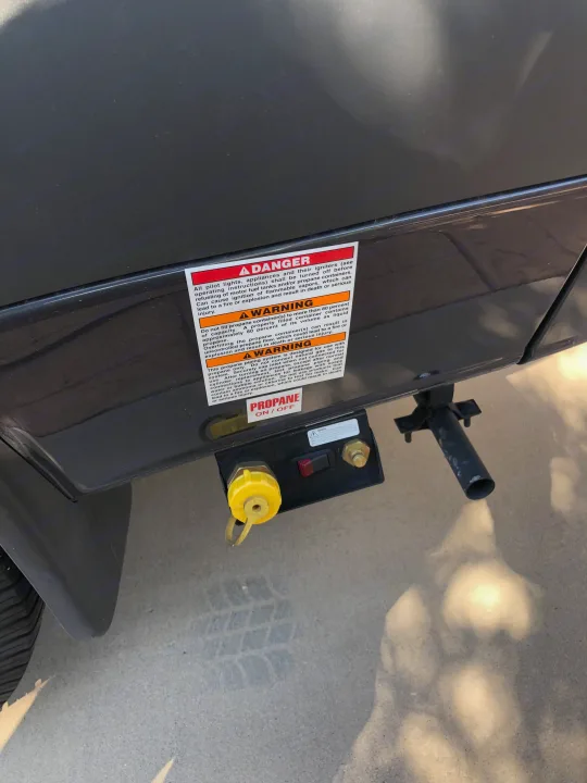 Propane connection panel on an RV rental, showing safety warnings and a yellow propane cap with an on/off switch.. Mercedes-Benz 4x4 Sprinter mwb 2021