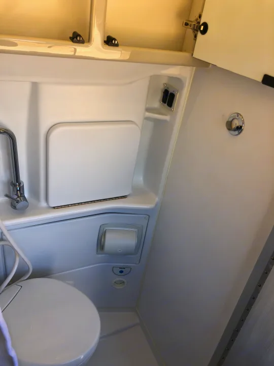 RV rental's compact wet bath features a toilet, sink with hinged cover, faucet, and light/fan controls. Efficient design.. Mercedes-Benz 4x4 Sprinter mwb 2021