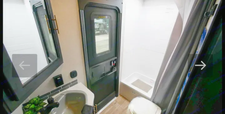 RV rental's compact bathroom: sink, mirror (left), main door (center), shower, toilet (right). Functional space.. Forest River Cherokee Grey Wolf 2021