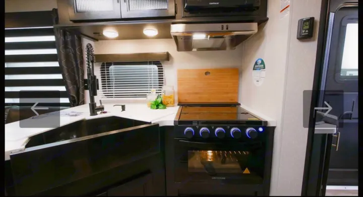RV rental kitchen: modern interior with black sink, oven, and microwave. Functional appliances and spacious counter.. Forest River Cherokee Grey Wolf 2021