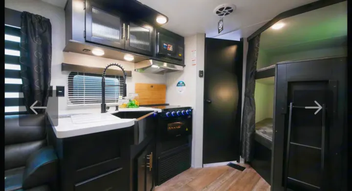 Explore this **RV rental's** modern interior: a full kitchen with sink, stove, microwave, and cozy bunk beds. Ideal for family adventures.. Forest River Cherokee Grey Wolf 2021