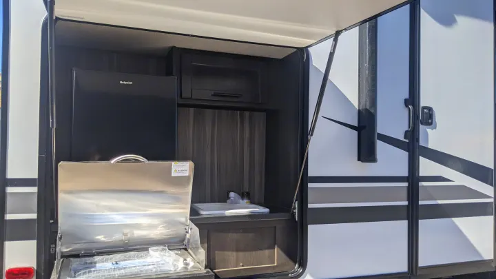 This RV rental features a convenient outdoor kitchen with a Hotpoint fridge, grill, and sink, perfect for camping.. Crossroads Cruiser Aire 2022