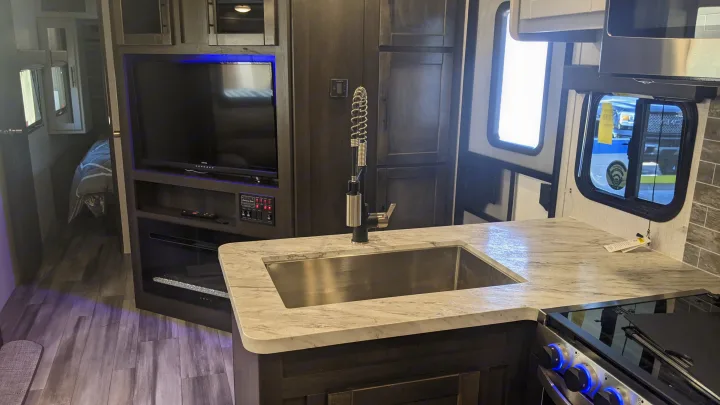 Experience comfort on the road with this modern RV rental interior, featuring a full kitchen, living area with TV, and cozy bedroom.. Crossroads Cruiser Aire 2022