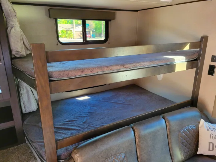 RV rental: Bright, modern interior featuring stacked bunk beds, a plush sofa, and a window view.. Grand Design 265bh 2021