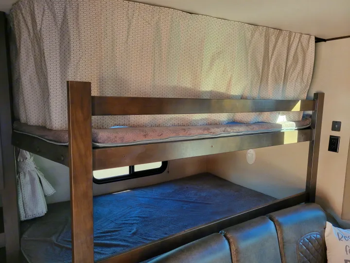 RV rental bunk beds featuring privacy curtains, cozy bedding, and charging ports for a comfortable stay.. Grand Design 265bh 2021