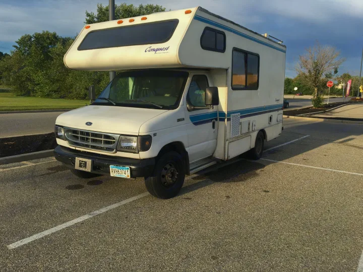 This white Ford E-350 motorhome, an ideal RV rental, is parked in a lot, ready for your next adventure.. Gulf Stream Conquest 1998