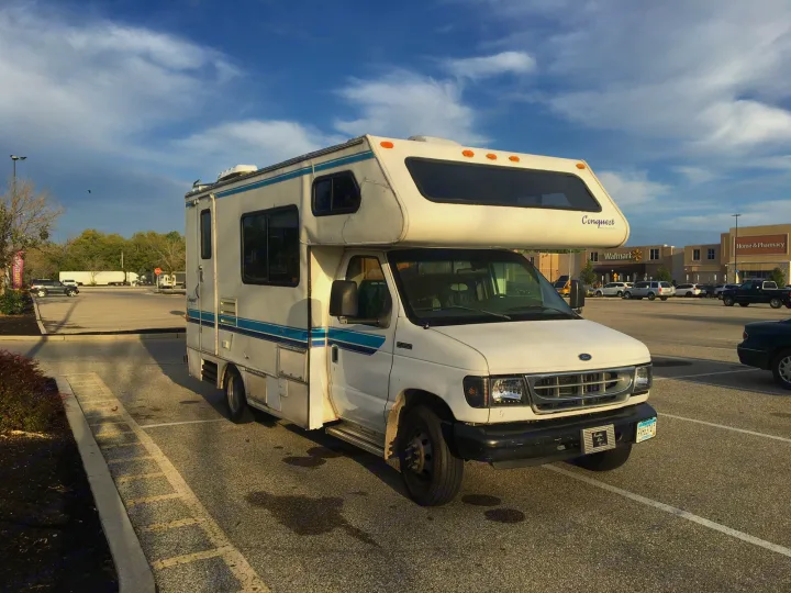 This white RV rental, a Ford E-350 camper, is parked in a sunny Walmart lot.. Gulf Stream Conquest 1998