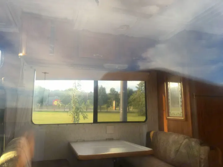 Enjoy an RV rental: comfy interior with a dinette, reflecting sky on the ceiling, and a bright view of green landscapes.. Gulf Stream Conquest 1998