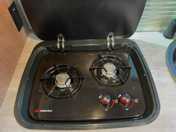 An open two-burner Suburban gas stove, ready for cooking in an rv rental or camper kitchenette.. Forest River R-Pod 2020