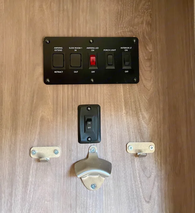 RV rental interior: control panel for awning, slide-out, and lighting, plus utility hooks and a wall-mounted bottle opener.. Forest River R-Pod 2020