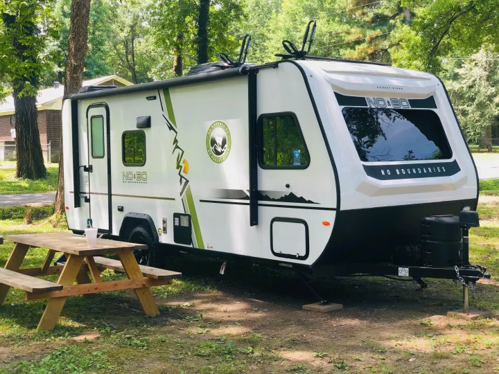 Enjoy your outdoor adventure with this Forest River No Boundaries RV rental, parked at a scenic campsite with a picnic table.. Forest River R-Pod 2020