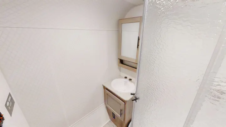 Step into a functional RV rental bathroom featuring a compact vanity, sink, and shower with patterned glass.. Forest River R-Pod 2020