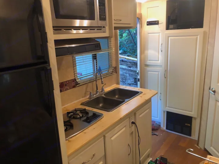 RV rental kitchen interior with a new wooden counter, double sink, gas stove, fridge, and microwave.. Cruiser RV Shadow Cruiser 2010