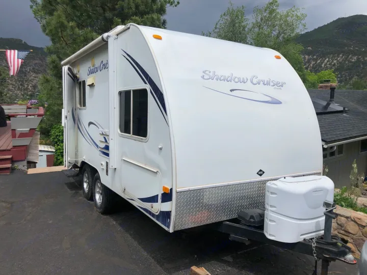 White Shadow Cruiser travel trailer parked outdoors, ready for your next RV rental adventure with mountains in background.. Cruiser RV Shadow Cruiser 2010