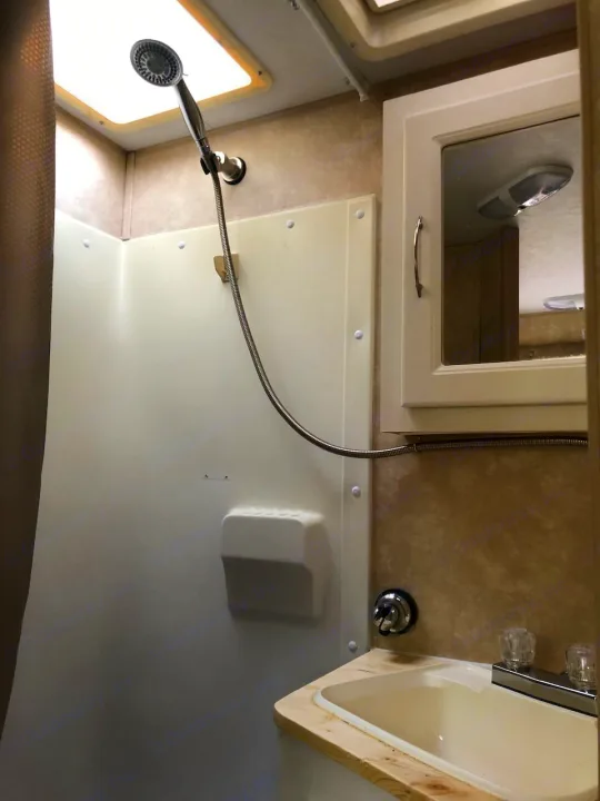 Inside an RV rental: a compact bathroom featuring a shower, sink, and mirrored cabinet.. Cruiser RV Shadow Cruiser 2010