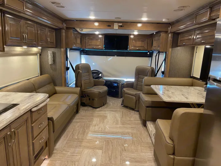 Inside a luxurious RV rental: Spacious cabin with leather seating, dining booth, kitchen, and driver's cockpit.. Thor Motor Coach Aurora 2020