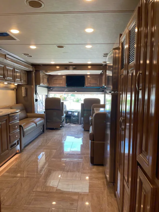 Inside a spacious RV rental: Sleek wood cabinets, luxurious leather seating, and gleaming tiled floors define this premium interior.. Thor Motor Coach Aurora 2020