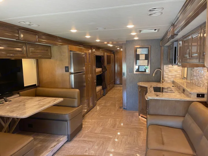 Luxury RV rental interior showcasing a spacious kitchen, dining area, and cozy bunk beds. Ideal for family adventures.. Thor Motor Coach Aurora 2020