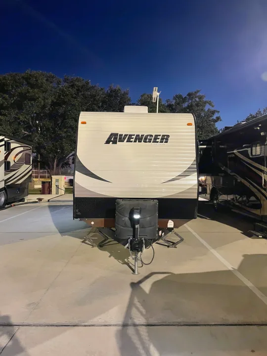 Front view of an Avenger travel trailer RV rental, parked at night. Its hitch and support jacks are visible.. Forest River Avenger 28RKS 2015