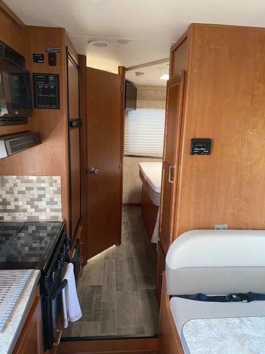 RV rental interior: Kitchen, hallway leading to the bed, and dining area visible in this well-appointed camper setup.. Winnebago Minnie Winnie 2019