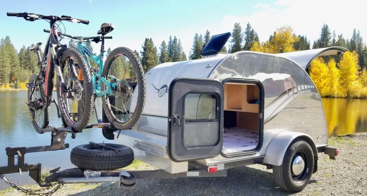 Teardrop camper **rv rental** with bikes by a scenic lake. Features solar panel & comfy bed for outdoor adventures.. Other Other 2011