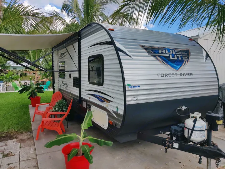 Parked Forest River Cruise Lite travel trailer with extended awning. Ideal rv rental for outdoor adventures amidst palm trees.. Forest River Salem 2018