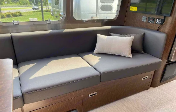 Comfortable RV rental interior with grey dinette seating, window views, and modern amenities.. Airstream Globetrotter 2022