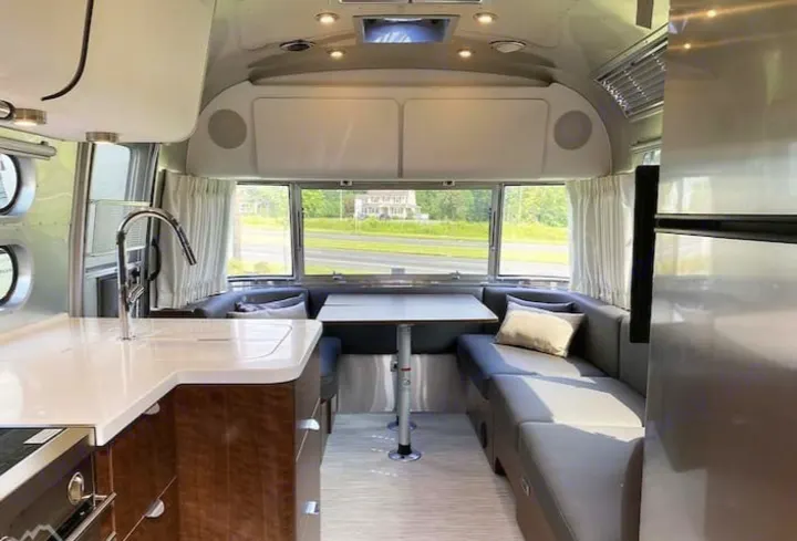 Spacious Airstream RV rental interior: modern kitchen, dining area, and lounge with scenic views through large windows.. Airstream Globetrotter 2022