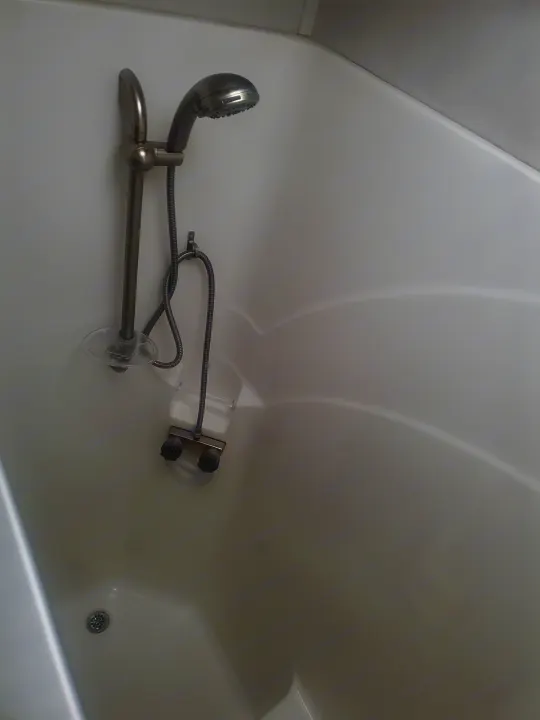 Clean, compact RV rental bathroom showing a white shower/tub, handheld showerhead, faucet handles, and drain.. Forest River Georgetown GT7 2021