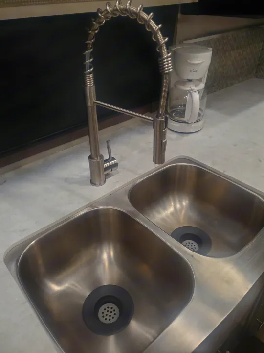 Clean RV rental kitchen with a double sink, modern faucet, and coffee maker on a light countertop.. Forest River Georgetown GT7 2021