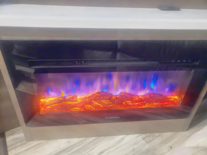 Cozy RV rental: Electric fireplace with vibrant blue and orange flames over artificial logs. Features realistic display, Furrion branded.. Forest River Georgetown GT7 2021