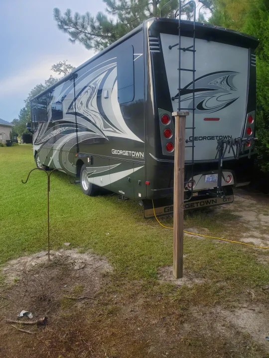 Georgetown RV rental. This spacious motorhome is parked on grass, featuring a rear ladder and bike rack for travel.. Forest River Georgetown GT7 2021