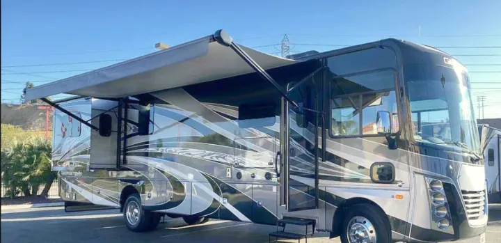 Stylish Class A motorhome RV rental with extended awning, parked outdoors on a bright, sunny day.. Forest River Georgetown GT7 2021
