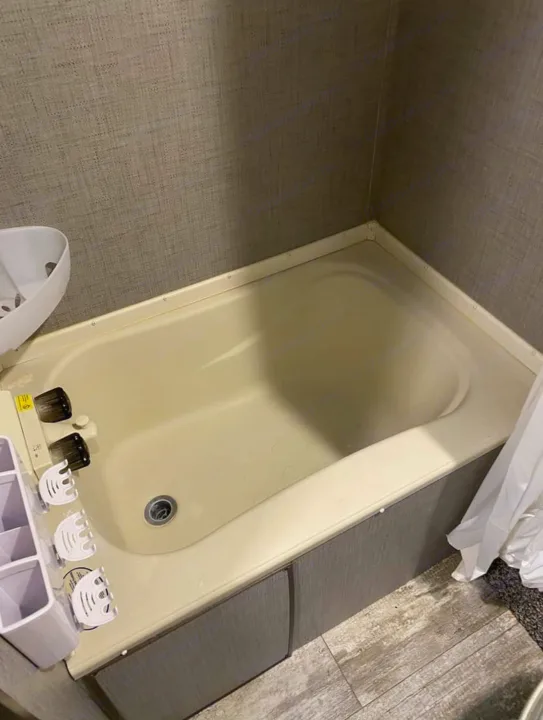 Compact bathroom with a light-colored bathtub, ideal for an RV rental. Features storage organizer, faucet, and shower curtain.. Crossroads Zinger 2018