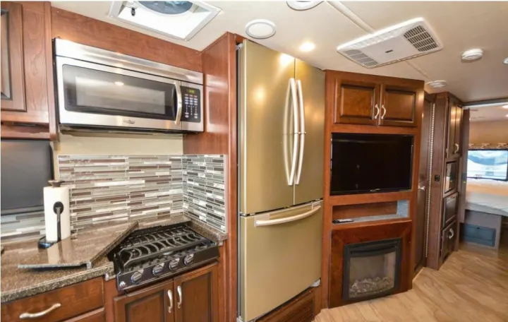 RV rental interior: Equipped kitchen (microwave, gas range, fridge), TV, & built-in fireplace.. Fleetwood Other 2017