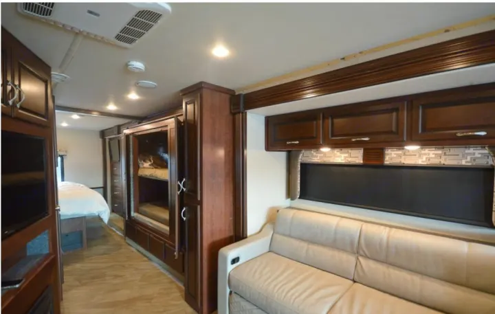 RV rental interior showcasing a bright living area, dark wood cabinetry, integrated bunk beds, and a rear bedroom.. Fleetwood Other 2017