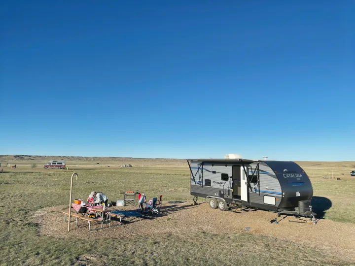 Enjoying the outdoors with an RV rental! A travel trailer is set up with a picnic table and campers under a clear sky.. Coachmen Catalina SBX 221TBS 2019