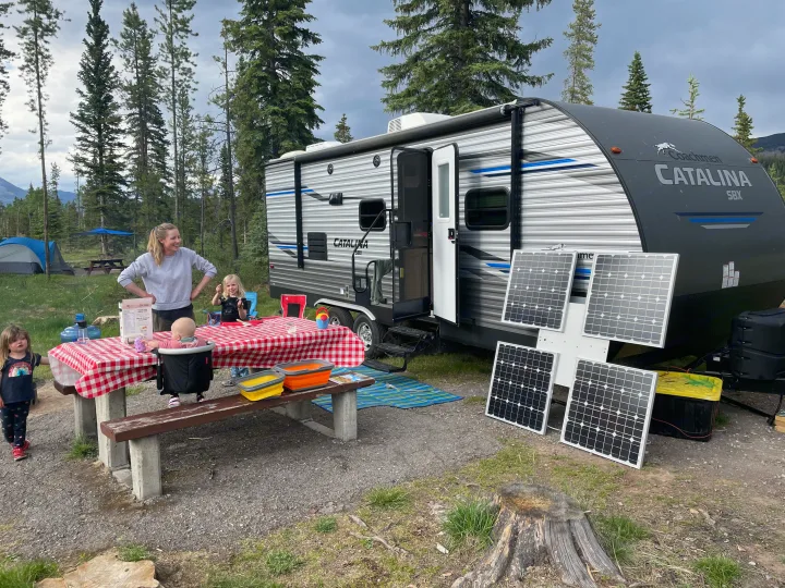 Family enjoying their RV rental at a scenic campsite with solar panels, a picnic table, & playful kids.. Coachmen Catalina SBX 221TBS 2019